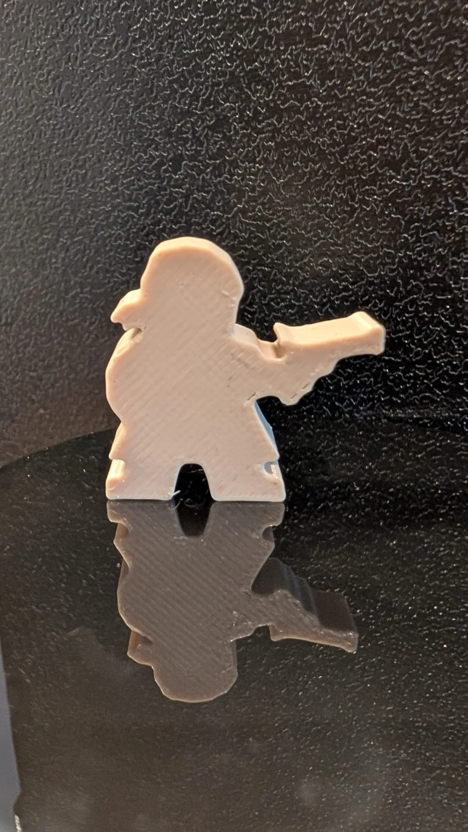 Gedruckte Figur mit angelegter Waffe, gespiegelt auf einer dunklen Fläche